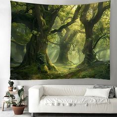 a living room with a white couch and large tapestry on the wall that has an image of a forest