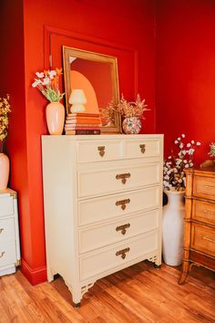 a white dresser sitting next to a red wall