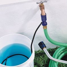 a bucket filled with blue liquid next to a hose