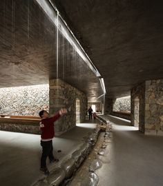 a man is standing in the middle of a room with stone walls and water flowing from it