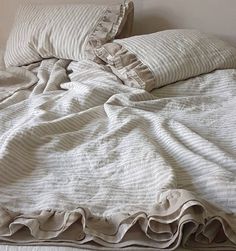 an unmade bed with two pillows on top of it and a blanket draped over the headboard