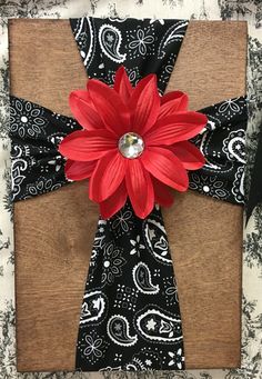 a cross made out of fabric with a red flower on the front and black background