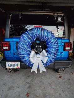 a blue jeep with a white bow on the tailgate