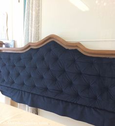 a blue headboard sitting on top of a bed next to a window with curtains