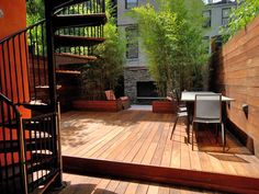 a wooden deck with chairs and table next to stairs leading up to a fire place