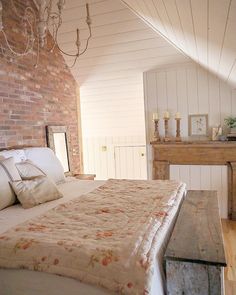 a bedroom with brick walls and white bedding, wooden furniture, and exposed ceiling