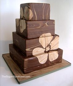 a three tiered cake made out of wood with flowers on the top and bottom