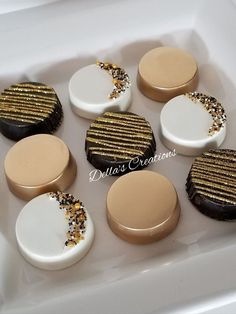 six cookies with gold and white frosting in a square box on a table top