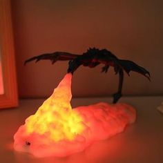 a glowing dragon figurine sitting on top of a table next to a framed photo