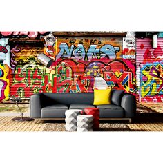 a couch sitting on top of a wooden floor next to a wall covered in graffiti