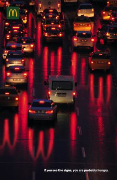 many cars are driving down the busy street at night, with red lights on them