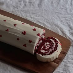 a cake with white frosting and red hearts on it sitting on a cutting board