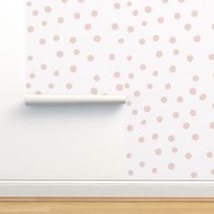 a white wall with pink dots on it and a wooden floor in front of it