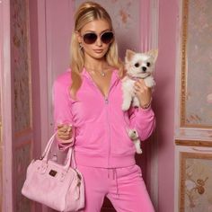 a woman holding a small white dog in her arms while wearing pink clothing and sunglasses