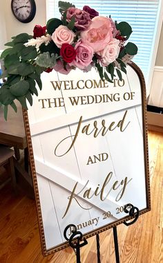 a welcome sign with flowers and greenery on it