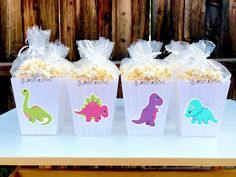 three plastic cups filled with popcorn sitting on top of a white table next to a wooden fence