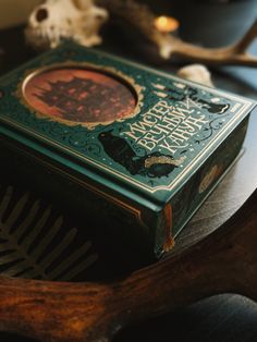 a green book sitting on top of a wooden table next to a deer skull and antlers