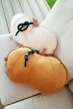 two pillows sitting on top of a couch next to each other in the shape of a pumpkin