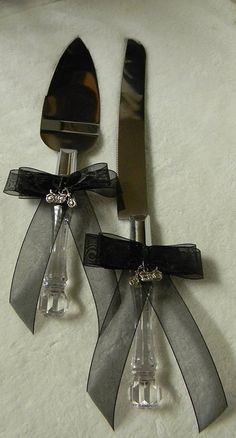 two forks and spoons with black bows on them sitting next to each other,