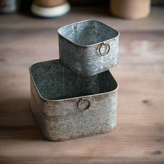 two metal containers sitting on top of a wooden table