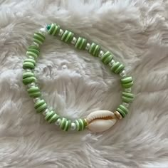 a green and white beaded bracelet with a shell