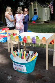 two women standing next to an ice bucket filled with popsicle sticks and candy bars