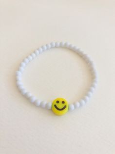 "customize your very own happy smiley face stretchy bracelet, made to order in your size! you will receive one white beaded bracelet with your choice of center smiley bead (gold or yellow). PLEASE NOTE: you will receive ONE bracelet with this order. these super trendy and versatile stretch bracelets are the perfect little accessory for your wrist. they are dainty and beautiful by themselves, but also look great when combined and stacked. you can add to your stack right here: http://www.etsy.com/ Handmade Accessories Bracelet, Bracelets With Smiley Faces, Handmade Beaded Jewelry Bracelets, Happy Face Bracelet, Simple Beads Bracelet, Ideas Para Hacer Pulseras, Simple Gifts For Friends, White Bead Bracelet, Body Jewelry Diy