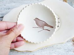 a hand is holding a plate with a bird on it