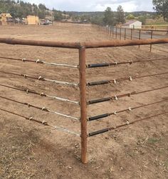 an old rusted metal fence in the middle of a dirt field with no grass