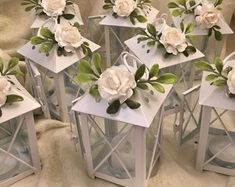 small white lanterns with flowers on them sitting on a blanket