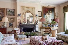 a living room filled with furniture and paintings on the wall behind a fire place in front of a fireplace