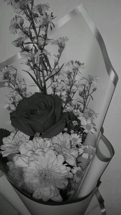 a black and white photo of flowers in a glass vase with a ribbon around it