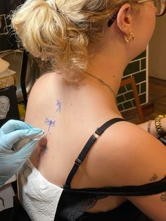 a woman with a tattoo on her back is getting inked by a manicurer