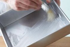 a person is using a knife to cut something in half on top of a metal tray