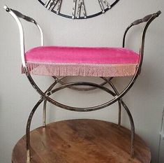 a pink bench sitting on top of a wooden table in front of a wall clock