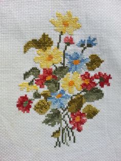 a bouquet of flowers is shown on a piece of white fabric with yellow, red and blue flowers in it