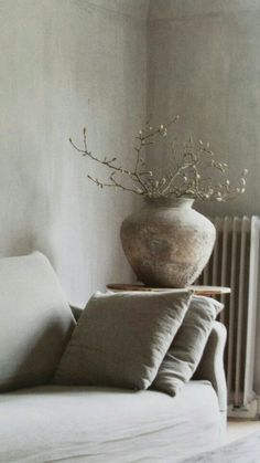 a white couch with pillows and a vase on top of it next to a radiator