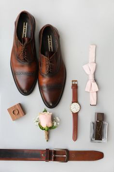 men's accessories laid out on a table including shoes, tie, watch and bracelet