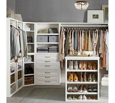 an organized closet with white drawers and chandelier