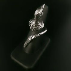 a silver ring with an eagle on it's head sitting on a black surface