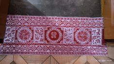 a red and white table runner sitting on top of a wooden floor