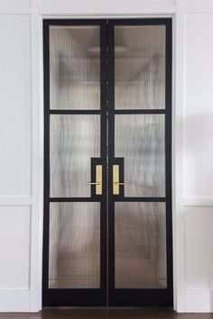 a black double door with gold handles and glass panels