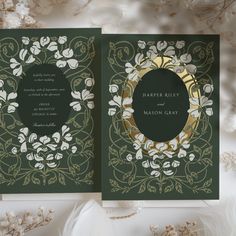 a green wedding card with white flowers and leaves on it, in front of a floral background