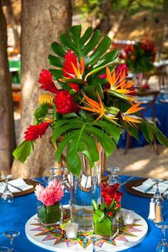 a vase filled with colorful flowers on top of a blue table cloth covered dining room table