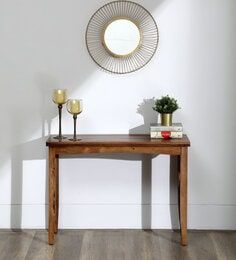 a wooden table with two candles and a mirror on the wall above it in a white room