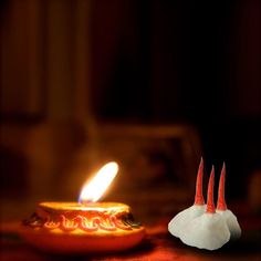 a lit candle sitting on top of a table next to a small white piece of paper