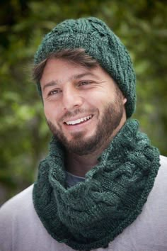 a man wearing a green knitted hat and scarf with a smile on his face