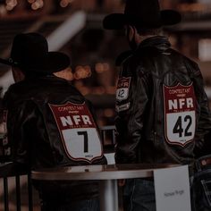 two men in cowboy hats are sitting at a table