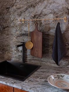 a kitchen sink sitting next to a counter top under a wooden cutting board on a towel rack