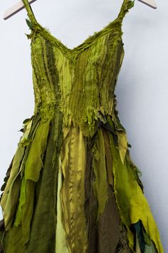 a dress made out of green fabric hanging on a white wall with clothes pins attached to it